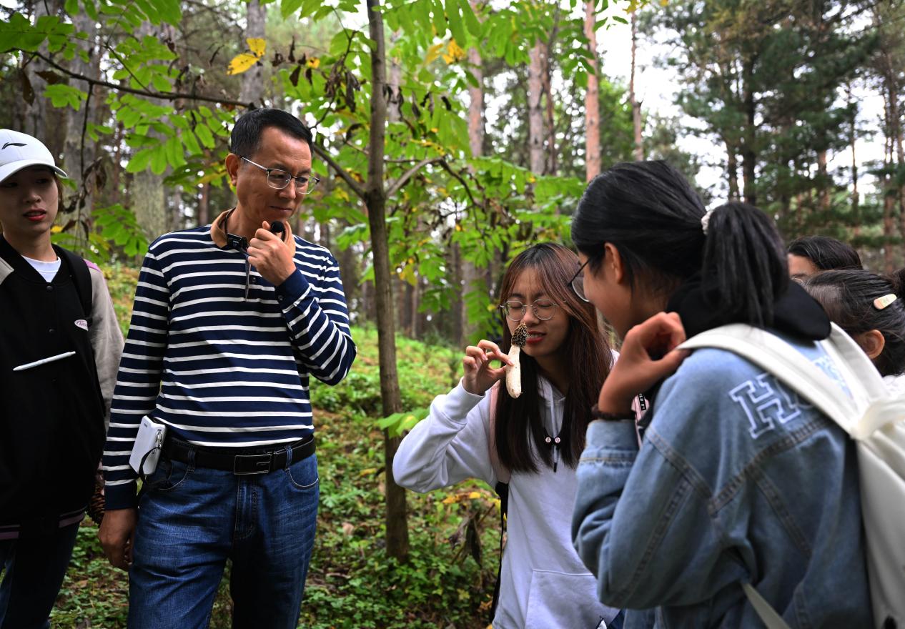 王占斌老師給同學(xué)們講解辨識蘑菇。（學(xué)校供圖）.jpg