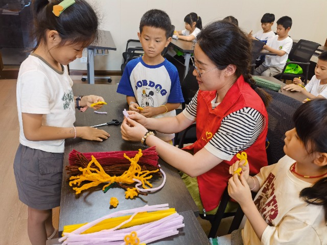 7月12日，在泰州市海陵區(qū)城東街道林湖社區(qū)，泰州市大浦小學(xué)“綠葉”暑期公益班的老師正在教孩子們一起做手工2（拍攝者：泰州市大浦中心小學(xué)  陳惠婷）.jpg